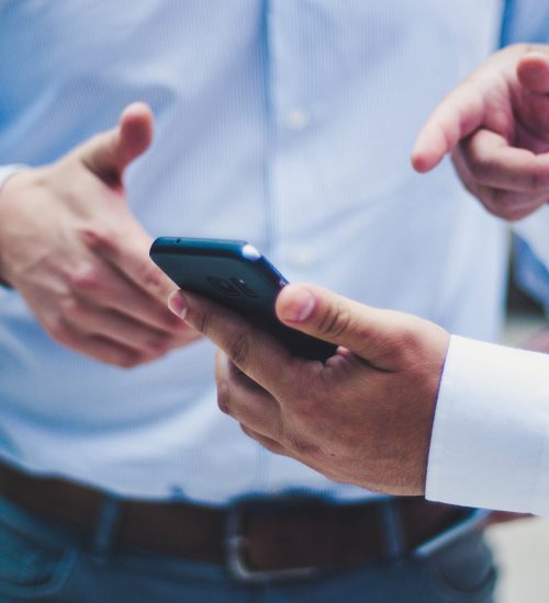 Two men looking at a phone and discussing